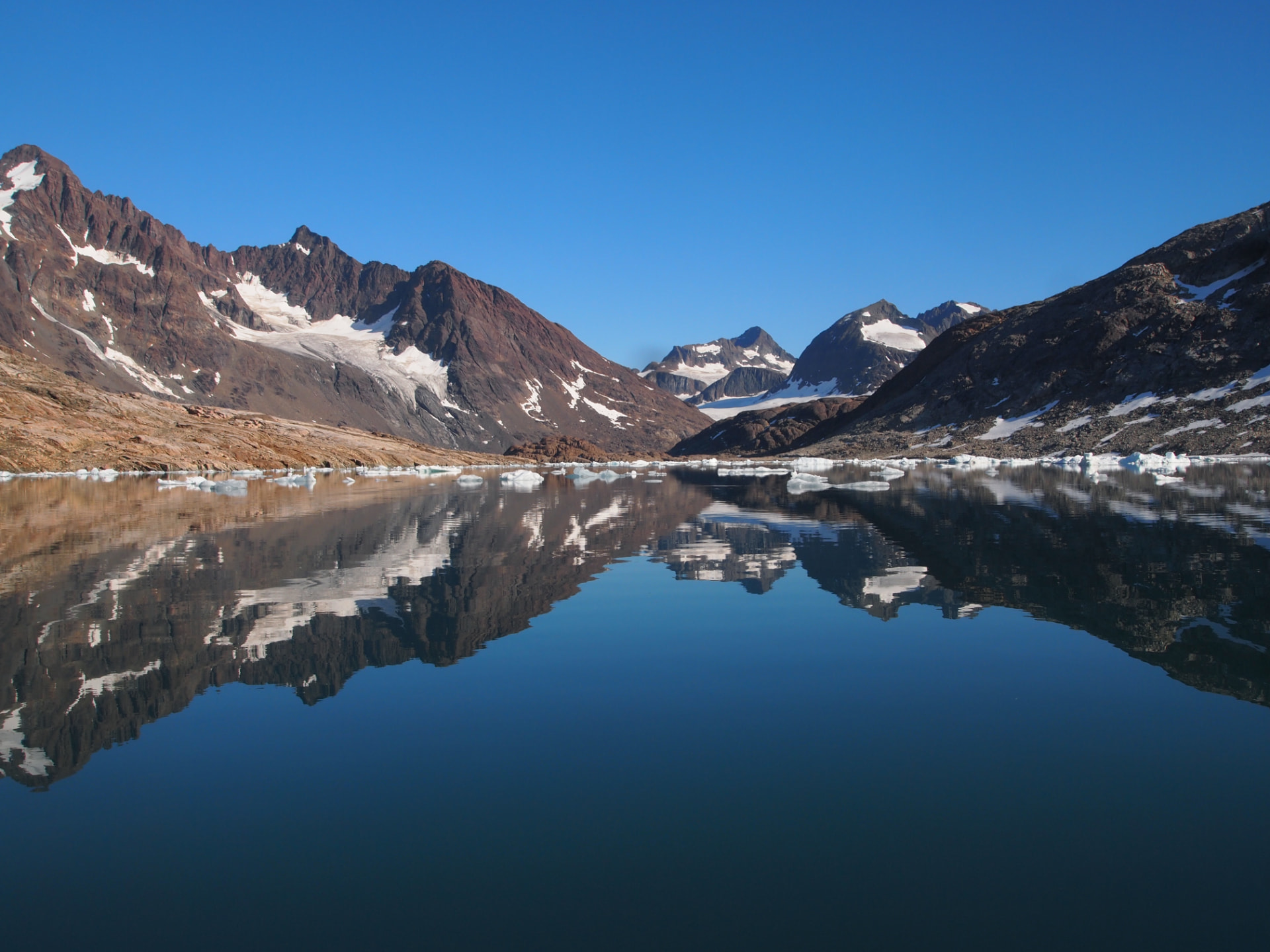 Skaergaard intrusion, East Greenland: mountains reflected in a still glacial lake with drifting ice